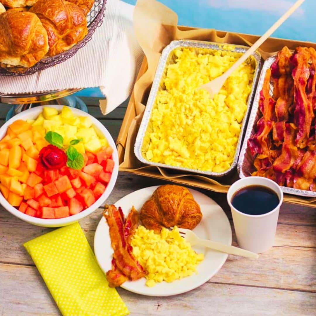 Trays of scrambled eggs and bacon along with a fruit bowl for breakfast catering near Midtown Manhattan NY.
