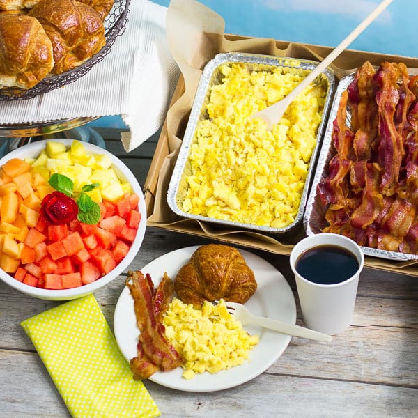 Trays of scrambled eggs and bacon along with a fruit bowl for Sugar Hill, Manhattan, New York office catering service.
