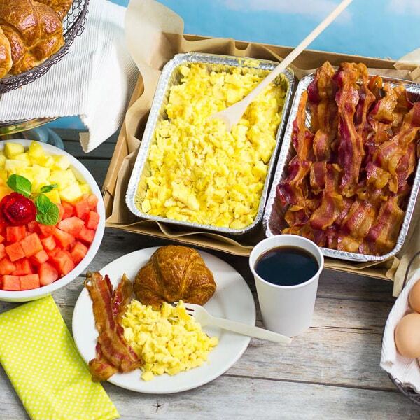 Trays of scrambled eggs, bacon, and fruit available for Harlem event catering services.